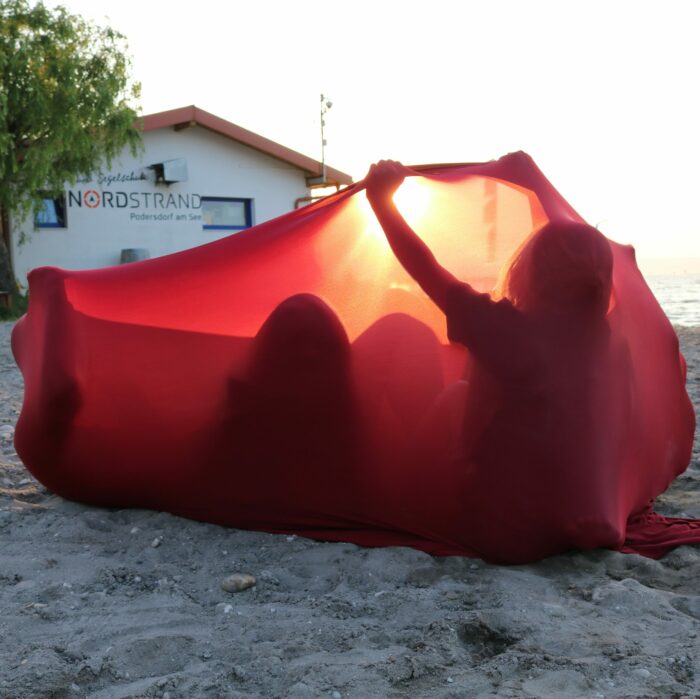 Familie mit Kindern entspannt am Strand im Erlebnistuch