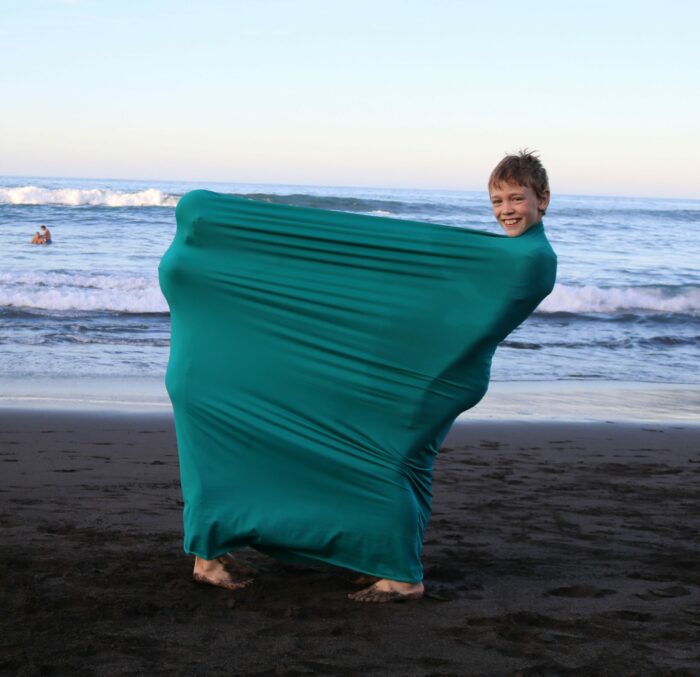 Zwei Volkschulkinder spielen am Strand mit dem Erlebnistuch