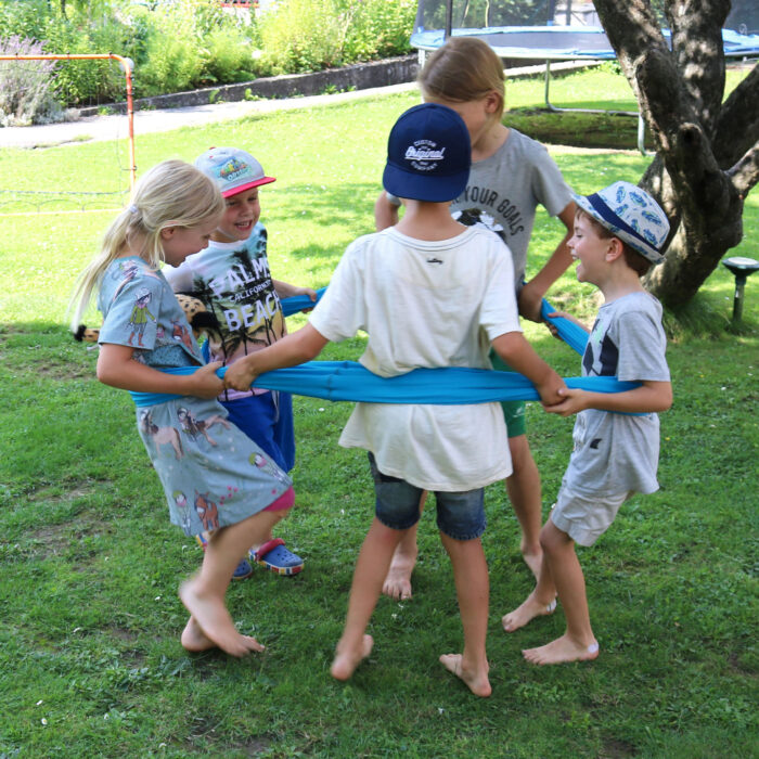 Kinder tanzen in einem Kreis im Erlebnistuch