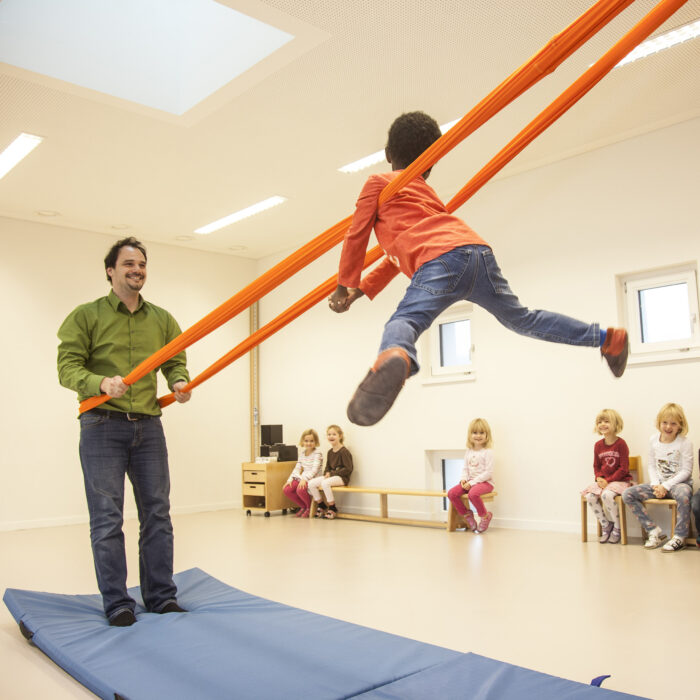 Foto: Kind im Turnsaal macht Übung mit Erlebnistuch