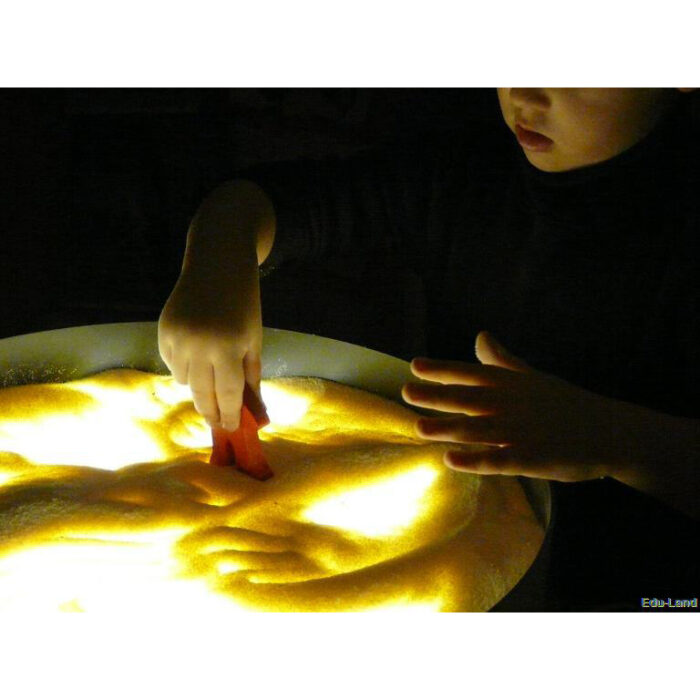 Foto: Kind spielt mit Gries auf gelb beleuchteter Leuchttonne