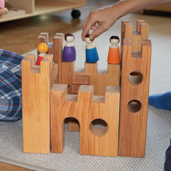 Kinder spielen mit der 10-teiligen Rittterburg aus Holz und den Holzfiguren von Bauspiel