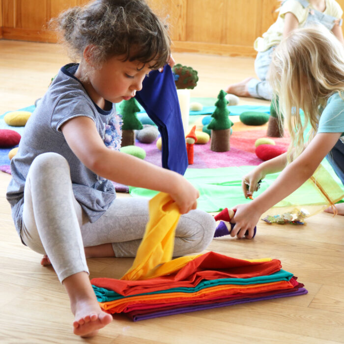 Kindergarten-Kind spielt mit Spieltüchern aus Baumwolle