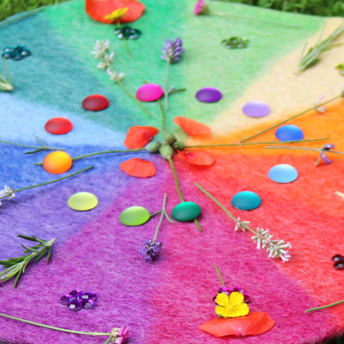 Mandala aus Blumen und matten Funkelsteinen auf dem Farbenkreis aus Filz