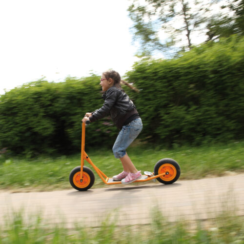 Kind im Vorschulalter braust auf dem robusten und sicheren Roller Scooter groß von beleduc durch den Garten