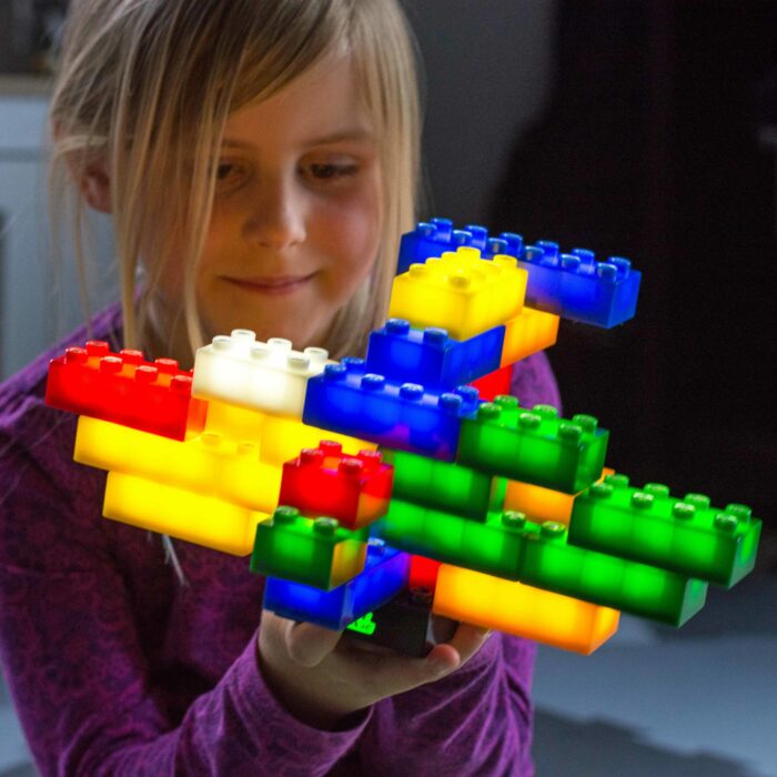 Kind im Kindergartenalter spielt mit den leuchtenden, Duplo® kompatibelen Leuchtbausteinen