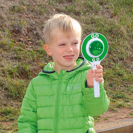 Kind hält Spielzeug-Polzeikelle mit grünem und rotem Licht
