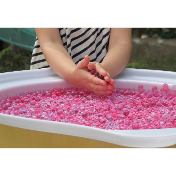 Foto: Kinderhände spielen mit rosa gefärbten Wunderperlen