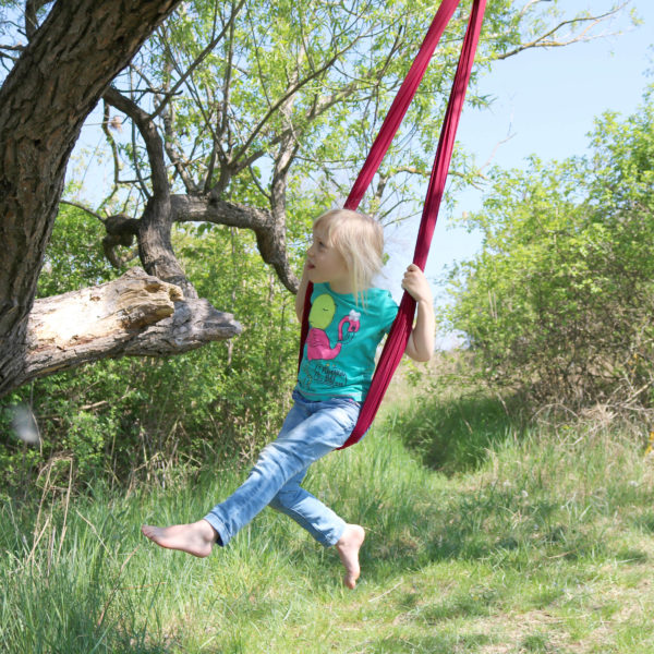 Foto: Kind schaukelt mit hängendem Erlebnistuch in der Natur