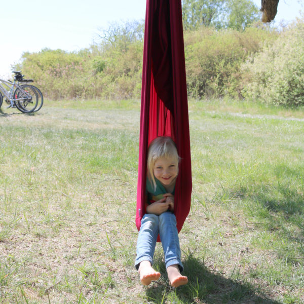 Foto: Kind sitzt in hängendem Erlebnistuch wie in einem Hängesessel