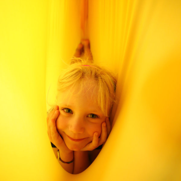 Foto: Kind liegt in gelbem Erlebnistuch, durch den Stoff strahlt das Licht