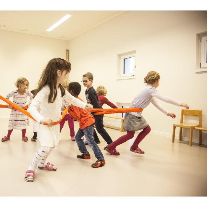 Foto: Kinder im Turnsaal machen Übung mit Erlebnistuch