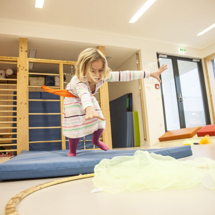 Foto: Kind im Turnsaal macht Übung mit Erlebnistuch