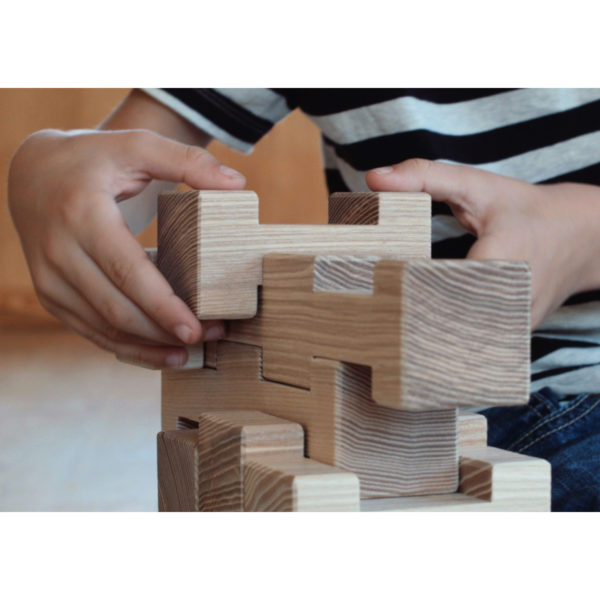 Kinderhände bauen einen Turm aus 4/4 Holzbausteinen