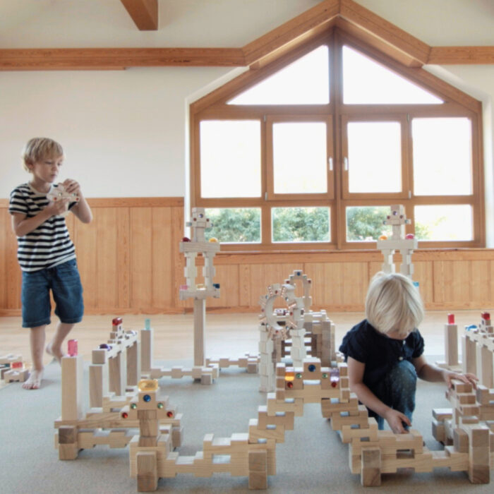 Kinder bauen große Burg aus 4/4 Holzbausteinen hergestellt in Österreich