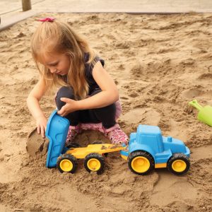 Foto: Kind spielt mit Traktor mit Anhänger in der Sandkiste