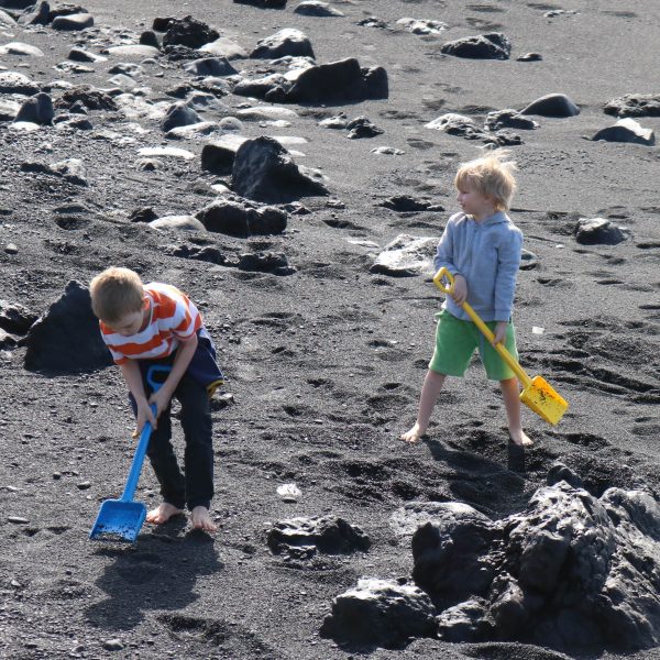 Foto: Kinder spielen mit großen Kinderschaufeln im Sand