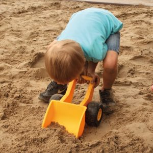 Foto: Kind schaufelt Sand mit dem Handbagger