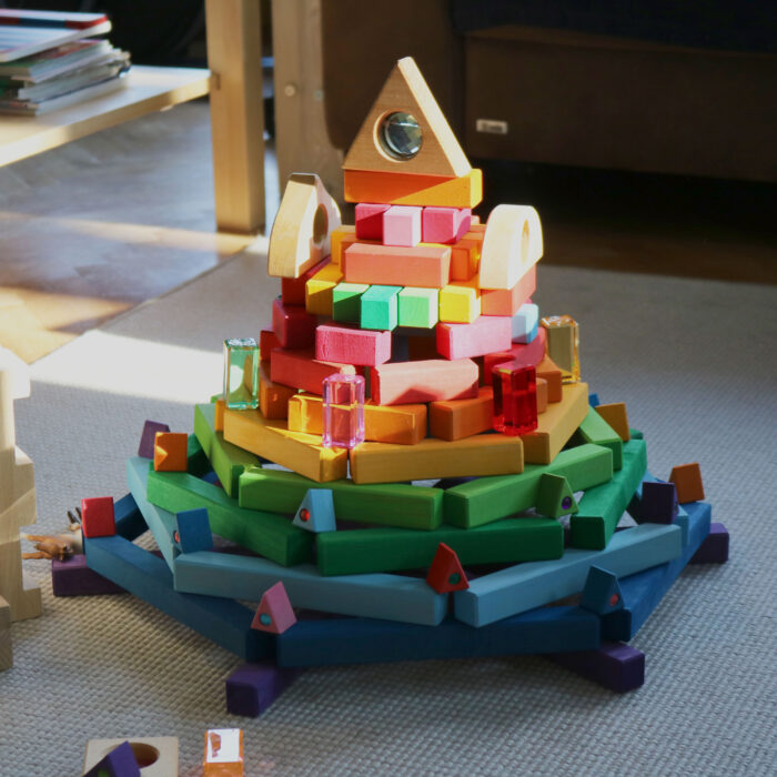 Ein Turm in Regenbogenfarben aus den Holzbausteinen der Bautreppe und anderen Bausteinen.