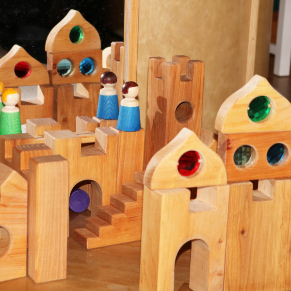 Nahaufnahme Holzbausteine für Kinder: Ritterburg mit Holzfiguren und Märchenschloss-Fenstern