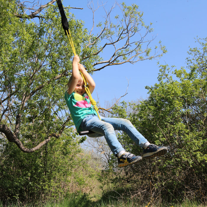 Kind schaukelt und dreht sich sitzend mit der "Turn & Swing" Schaukel