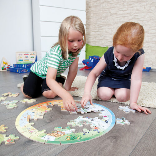 2 Kinder im Kindergartenalter sitzen am Boden um das runde XXL Lernpuzzle von beleduc