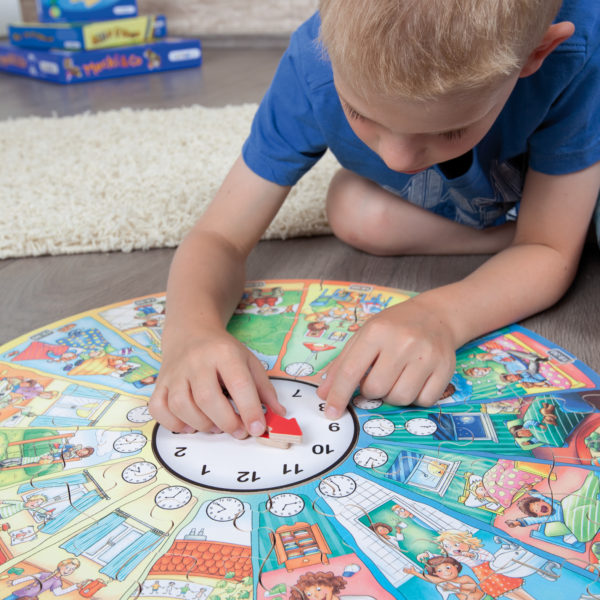 Bub im Kindergartenalter spielt mit dem Lernpuzzle Mein Tag und der integrierten Lernuhr.