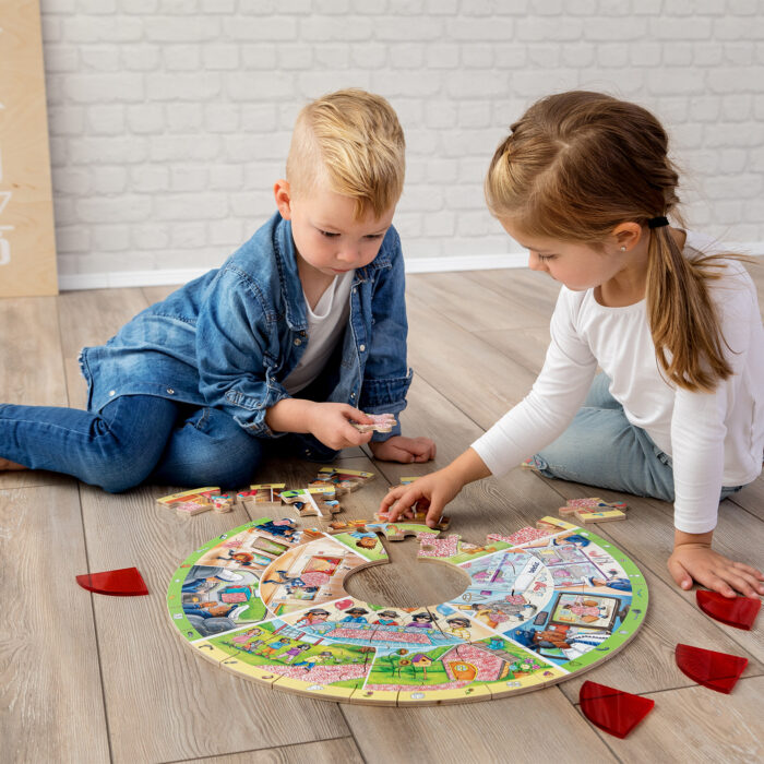 2 Kinder im Kindergartenalter sitzen am Boden und um das runde XXL Lernpuzzle von beleduc