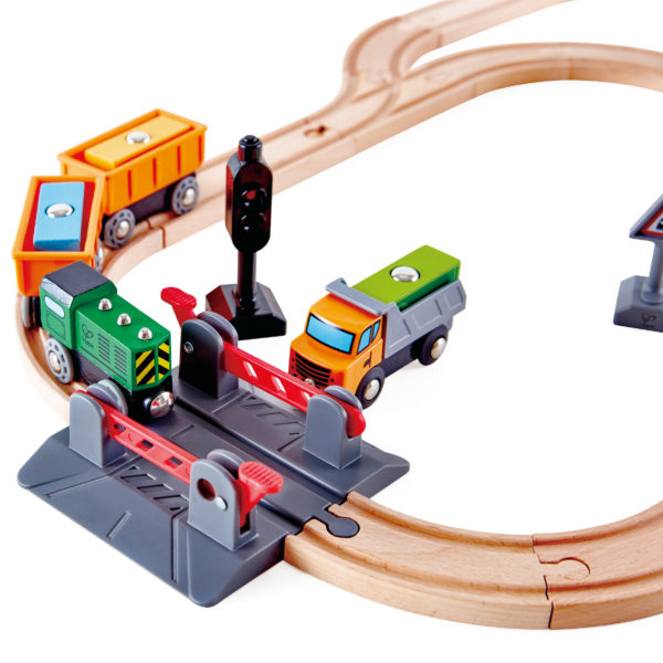 Detailsansicht des Holzeisenbahn-Sets von beleduc für Kinder ab 3 Jahren. Zu sehen die Schienen mti dem Bahnübergang und dem Güterzug