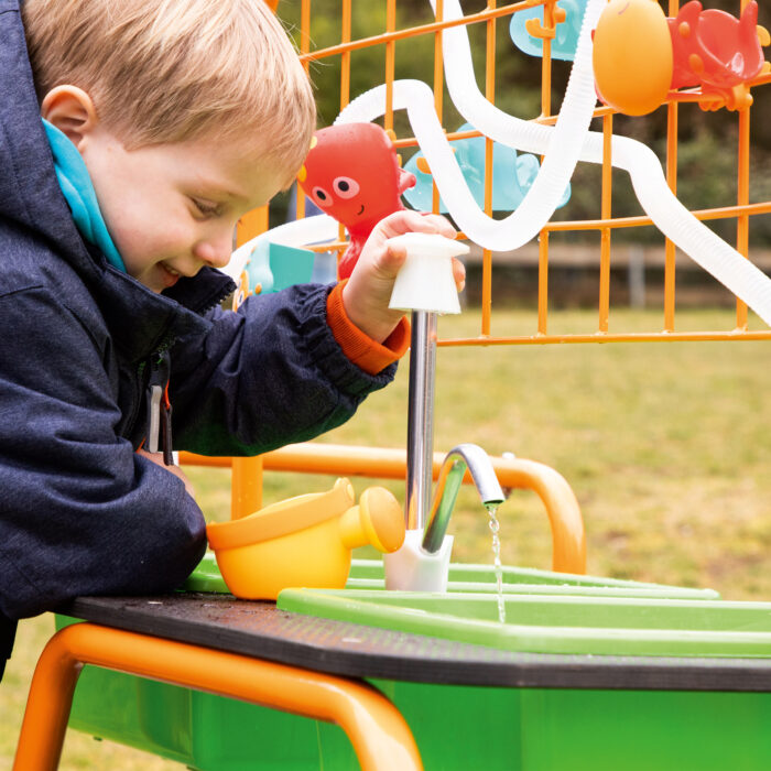 Bub im Kindergartenalter pritschelt vergnügt im Wasserbehälter