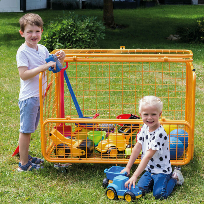 Ein Bub und ein Mädchen im Kindergartenalter vor dem gefüllten Transportwagen von beleduc