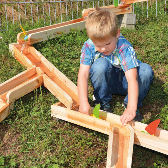 Kind spielt mit Wasserbahn aus Holz