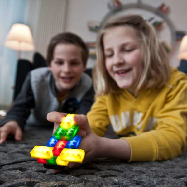 Zwei Buben im Volksschulalter spielen mit den leuchtenden, Lego® kompatibelen Leuchtbausteinen