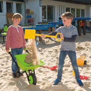 Kinder spielen mit Scheibtruhe im Sand
