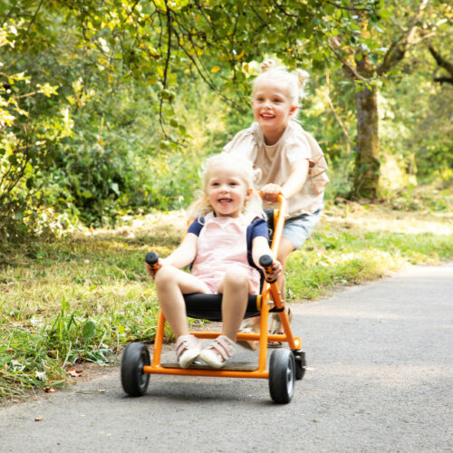 Mädchen schiebt anderes Kind das im Toptrike Buggy sitzt