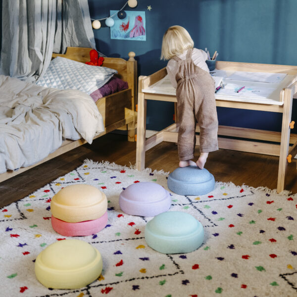 Kind balanciert über die 6 Stapelsteine in Pastelfarben aus dem Pastel Set