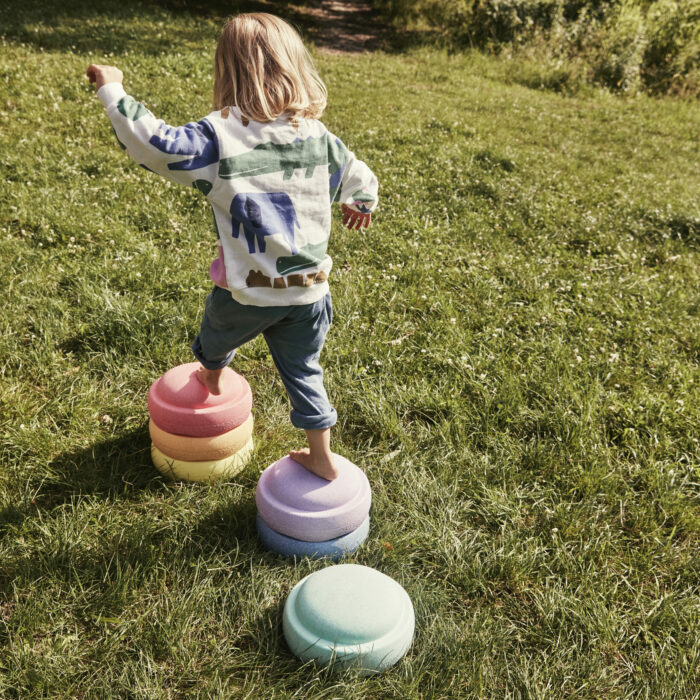 Kind balanciert über die 6 Stapelsteine in Pastelfarben aus dem Pastel Set