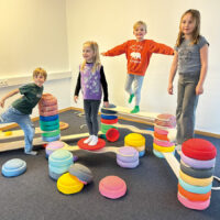 Kinder bauen Parcours aus Stapelseinen und Balancebrücken Set