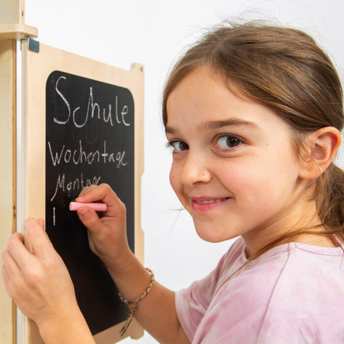 Kind schreibt auf Tafel von Spielschule