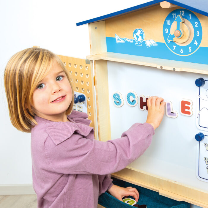 Kind legt Buchstaben auf Spielschule