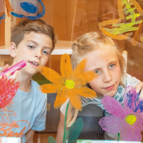 Kinder malen mit Creme Kreide auf Fenster