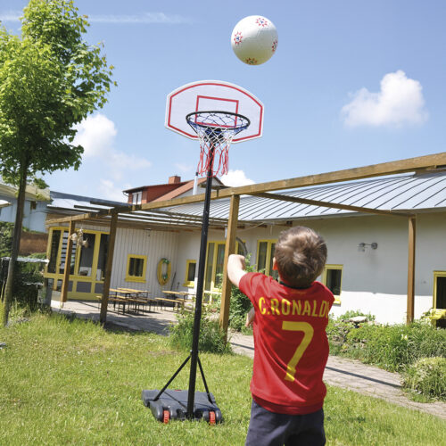 Kind spielt mit Basketball und wirft in Basketballständer